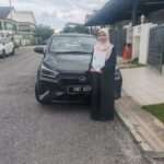 Pelajar UPM bergambar sendirian di depan Perodua Axia Grey selepas berjaya melalui Skim Pelajar Perodua