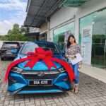 Pelajar kolej bergambar sendirian di depan Perodua Axia Coral Blue selepas proses Skim Pelajar Perodua bersama penjamin